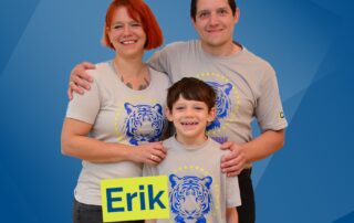 Lächelnde Familie mit Mama, Papa und im Vordergrund der Sohn.