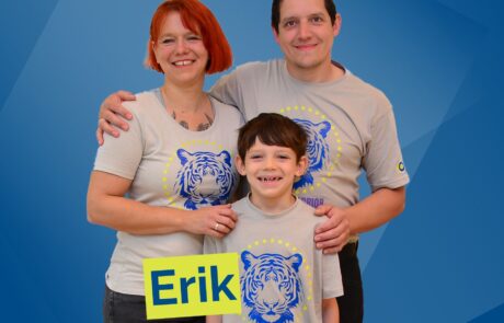 Lächelnde Familie mit Mama, Papa und im Vordergrund der Sohn.